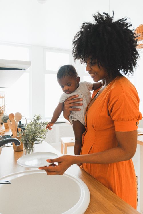 A mother holding her baby in a bright kitchen at home